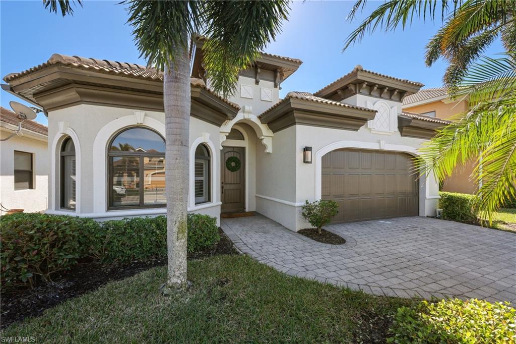 Stucco exterior featuring arched windows, a tile roof, and an integrated two-car garage