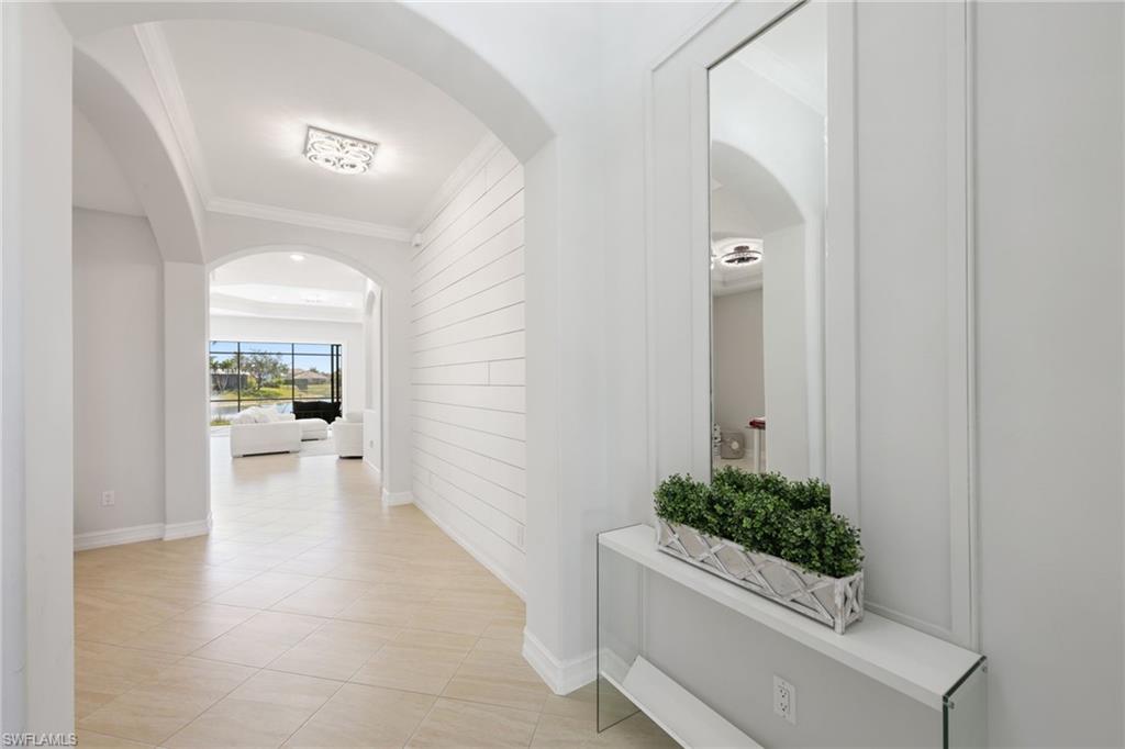 Entryway featuring light-toned tile flooring, archways, and a shiplap accent wall