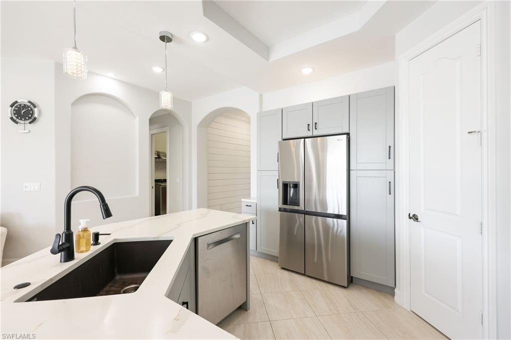 Kitchen featuring a large central island with a dark sink and matte black faucet, light-toned countertops, and recessed lighting