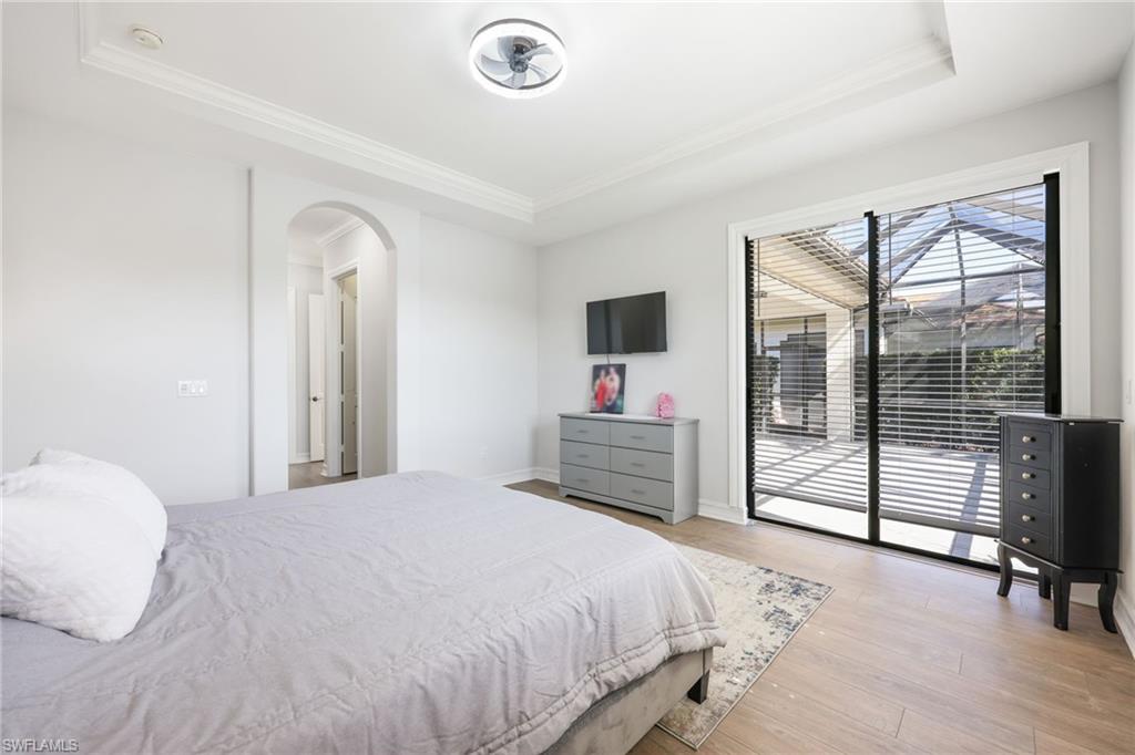 Recessed ceiling with crown molding, wood-finish flooring, and a contemporary ceiling fan
