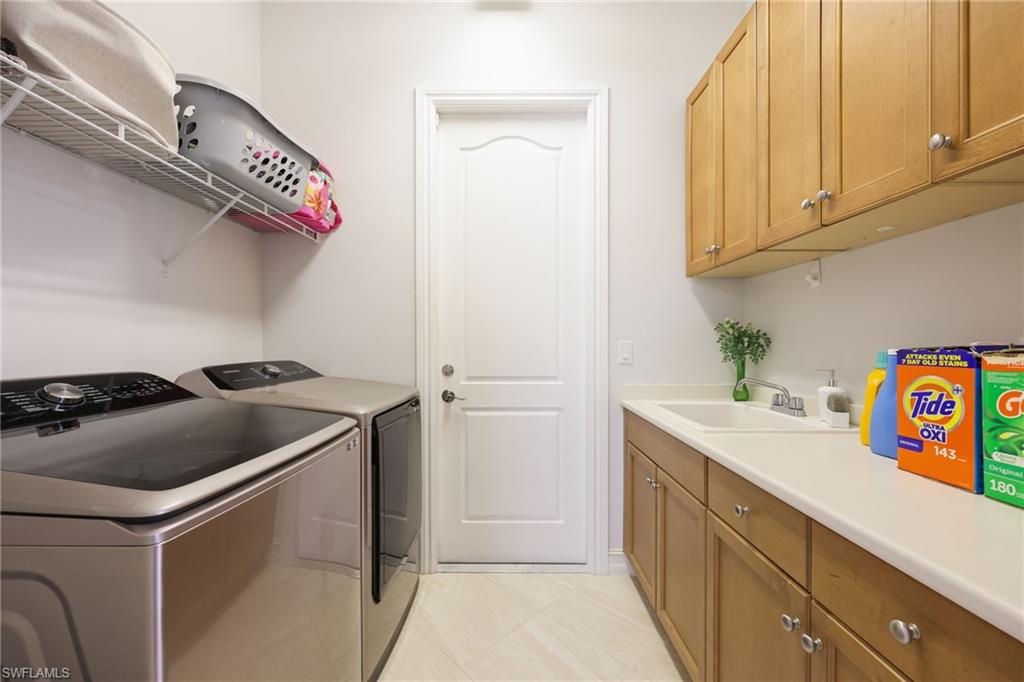 Practical utility room featuring a built-in sink, wood-finish cabinetry, a white countertop, and tiled flooring
