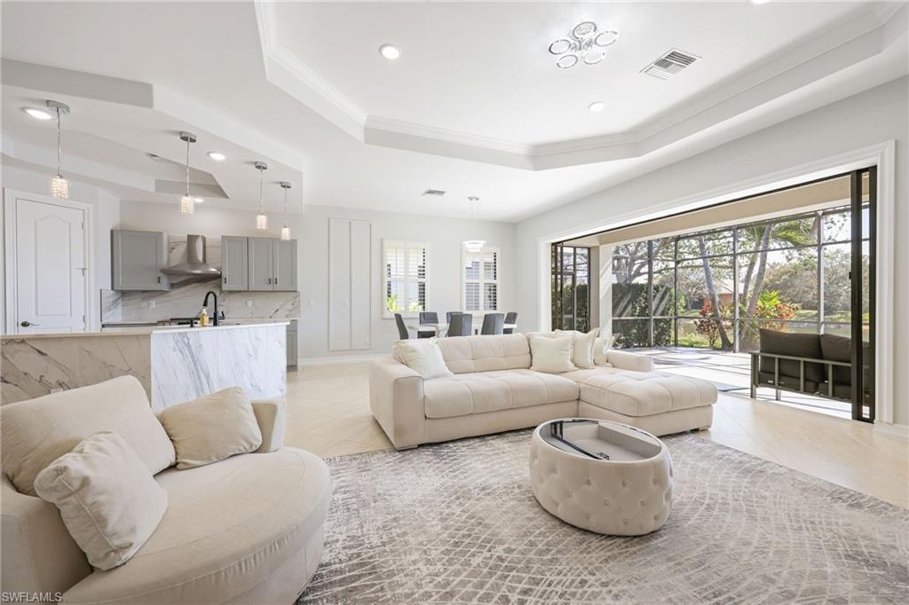Open-concept living area with tray ceiling, recessed lighting, and large format tile flooring