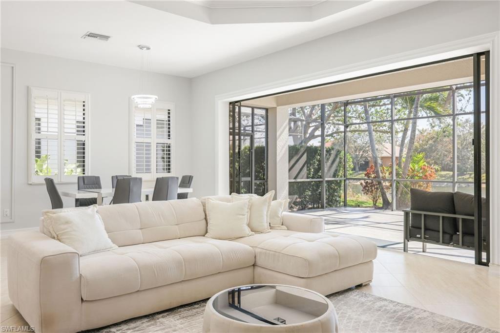 Expansive living area with large format tile flooring, a tray ceiling, and recessed lighting