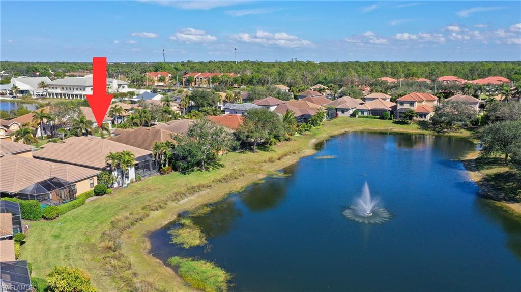 Aerial perspective highlighting a residential property with a tile roof and screened enclosure, situated alongside a body of water featuring a fountain