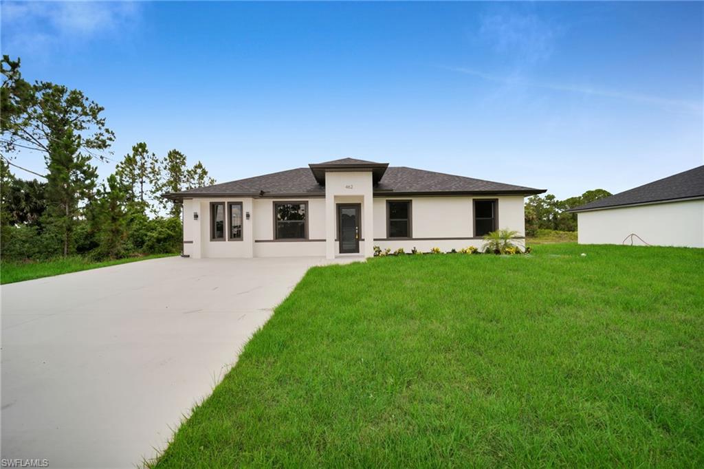 Contemporary single-story residence featuring a dark shingle roof, white stucco exterior, dark window trim, and a covered entry