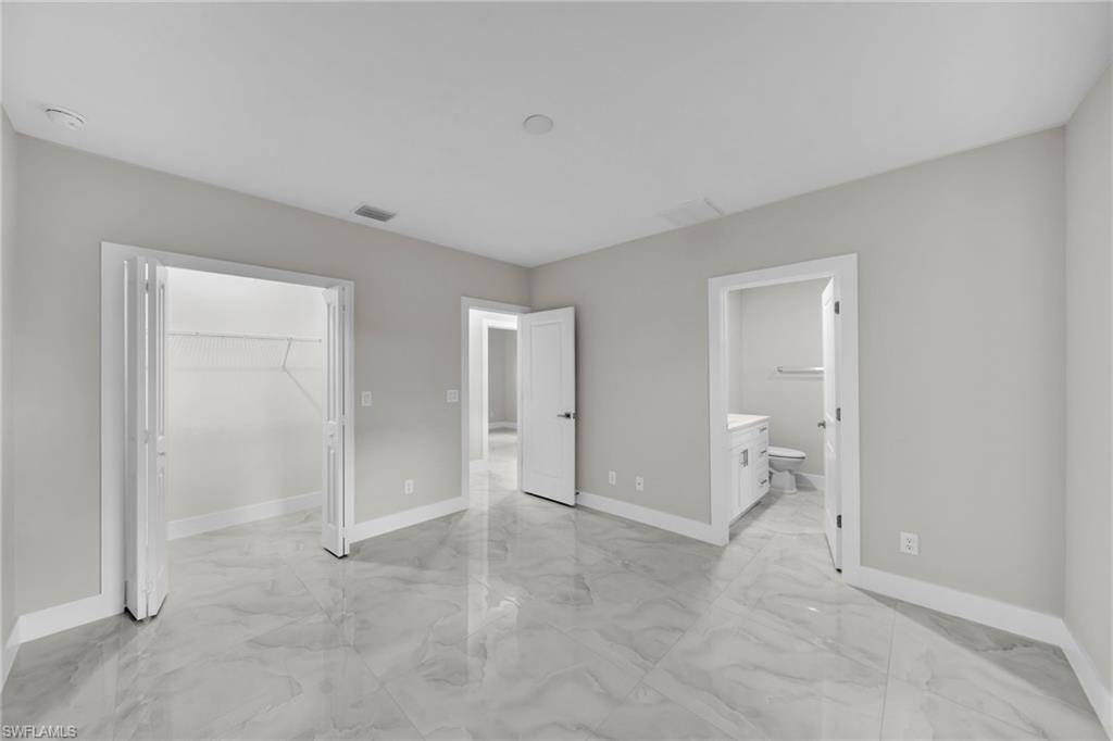 Spacious interior featuring large format tile flooring, light gray wall finishes, white trim, and a double-door closet
