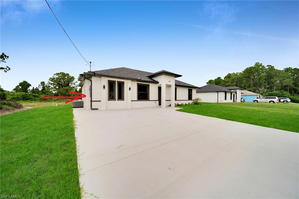 Contemporary white stucco exterior with dark trim accents, featuring a deep asphalt shingle roof