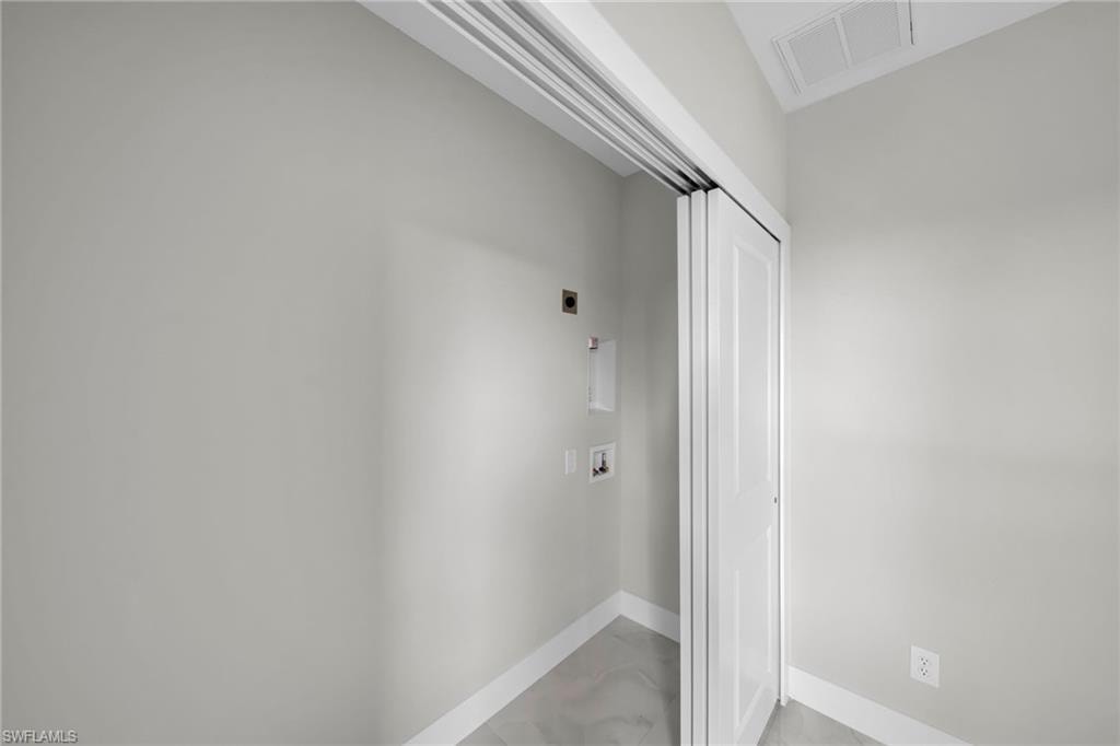 Laundry area featuring bi-fold doors, grey tile flooring, and light grey wall paint
