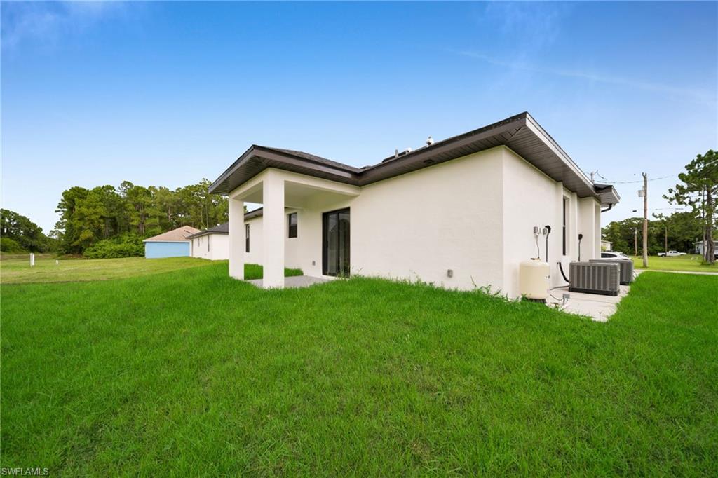 Contemporary white stucco exterior with a covered patio, dark roofline, and dual outdoor HVAC units on a concrete pad