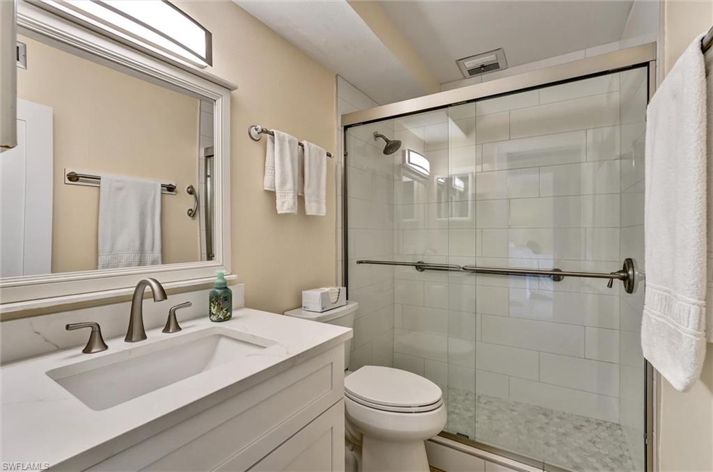 Tiled walk in shower with glass shower door and quartz vanity top