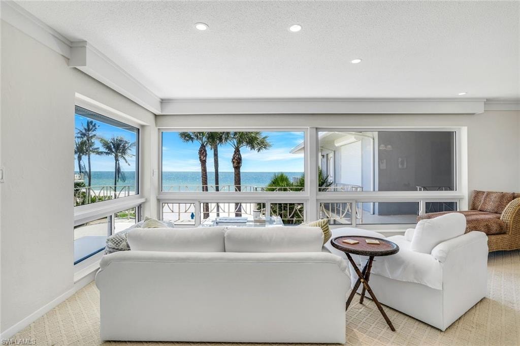 Living area featuring light colored carpet, a water view, recessed lighting, and ornamental molding
