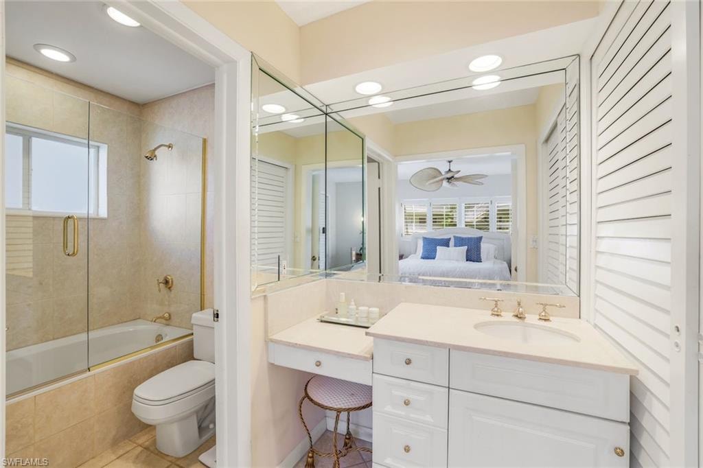 Bathroom with tiled shower / bath combo, connected bathroom, vanity, light tile patterned floors, and ceiling fan
