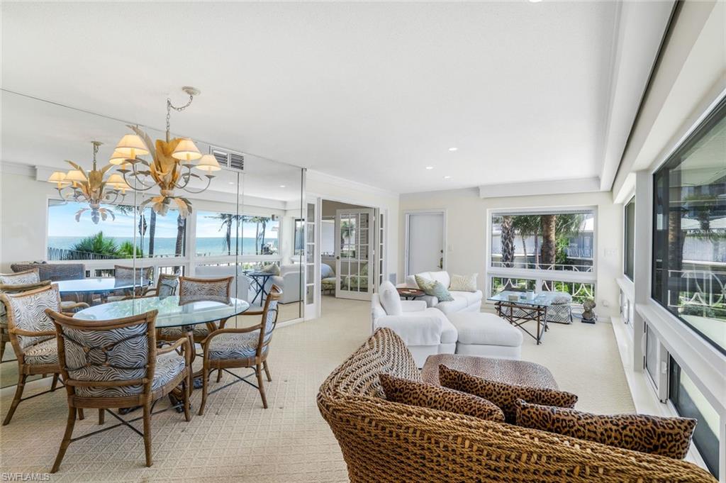 Dining space featuring light colored carpet, a chandelier, and plenty of natural light