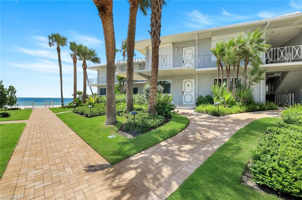 View of front of house with a balcony, a front yard, and a water view