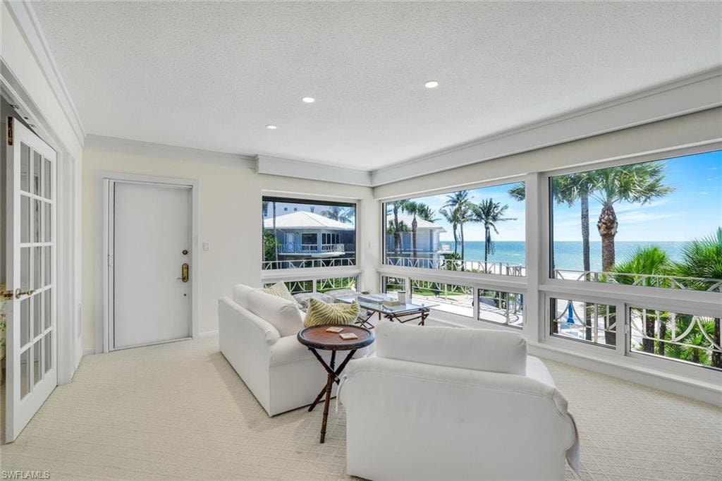 Carpeted living area with a water view, recessed lighting, and a textured ceiling