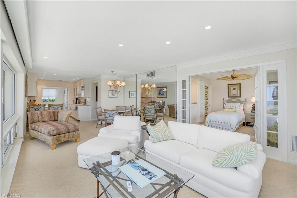 Carpeted living area with recessed lighting, ornamental molding, a chandelier, and ceiling fan