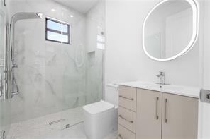 Modern bathroom featuring a glass-enclosed shower with a rainfall showerhead, large format wall tiles, a built-in shower niche, and a contemporary vanity with an integrated sink and illuminated mirror