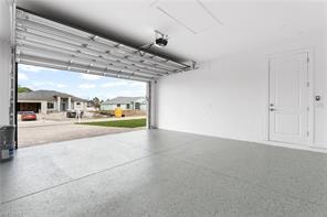 Spacious garage featuring a durable epoxy-coated floor, automatic overhead door, and a dedicated side door entry