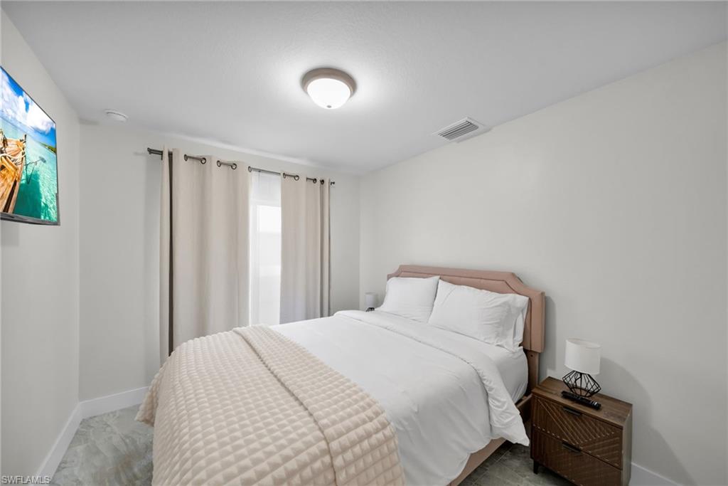 Bedroom featuring a flush-mount ceiling light, white walls, and a wall-mounted television