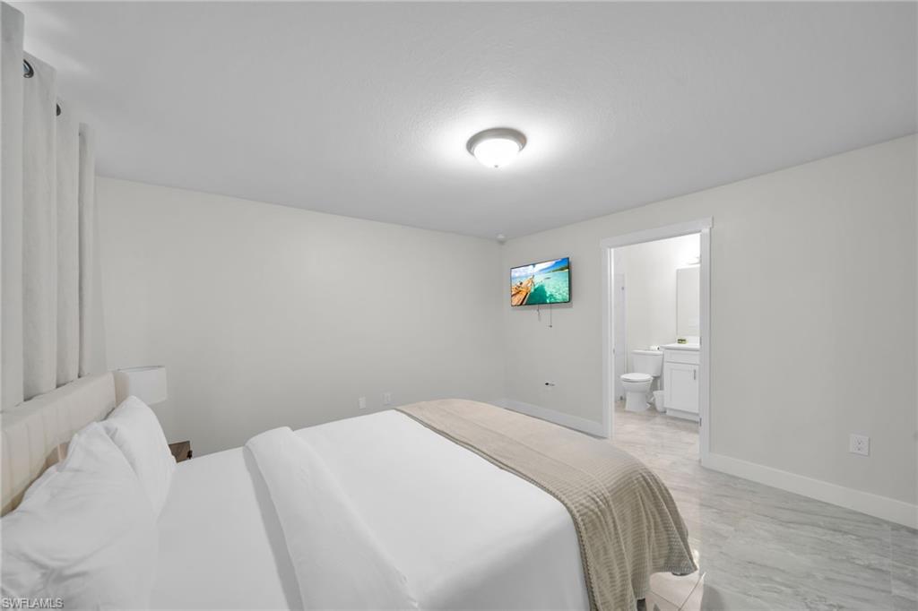 Spacious room featuring light-colored walls and a wall-mounted television