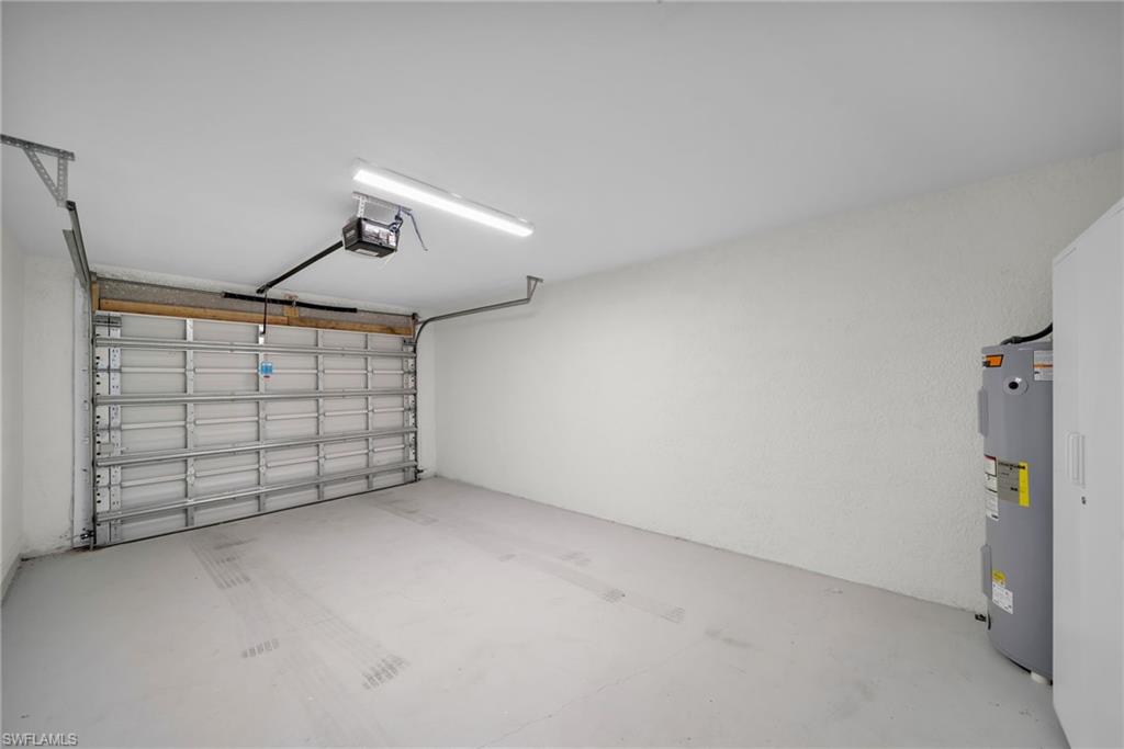 Spacious garage featuring a concrete floor, automatic garage door opener, and a water heater