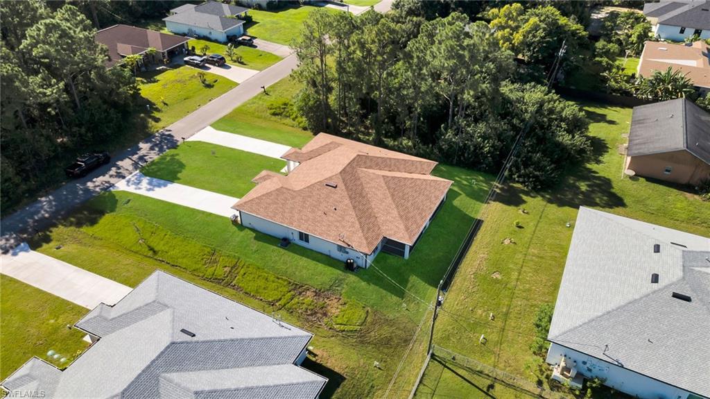 New construction home featuring a light brown shingle roof, white exterior, and an expansive concrete driveway