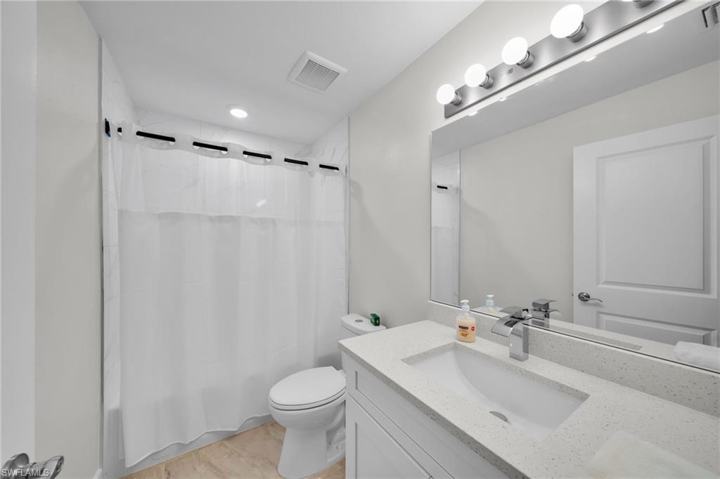 Bathroom featuring a white vanity with an integrated sink, polished chrome faucet, and a large mirror