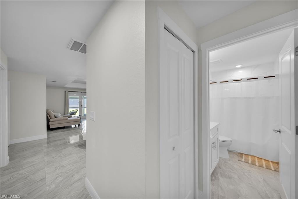 Hallway featuring light-toned flooring, white walls, and a bi-fold closet