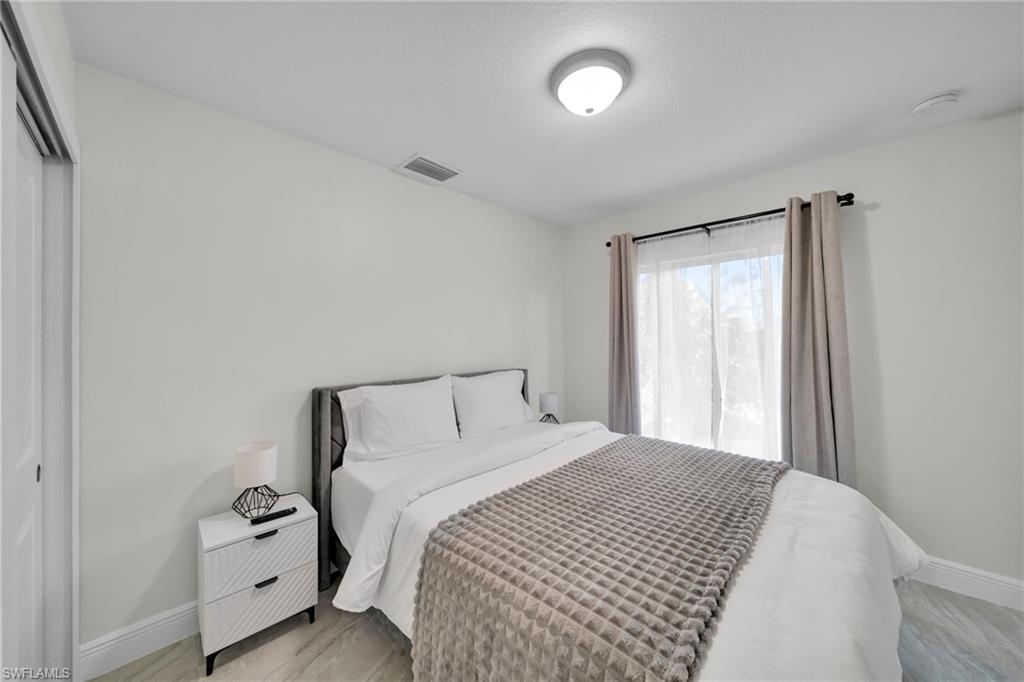 Bright room featuring light-toned walls, a window with sheer and blackout curtains, and light wood-finish flooring
