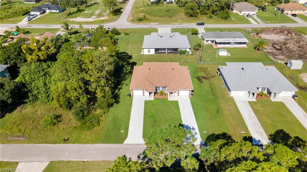 Aerial overview showcasing multiple properties with expansive green lawns and concrete driveways