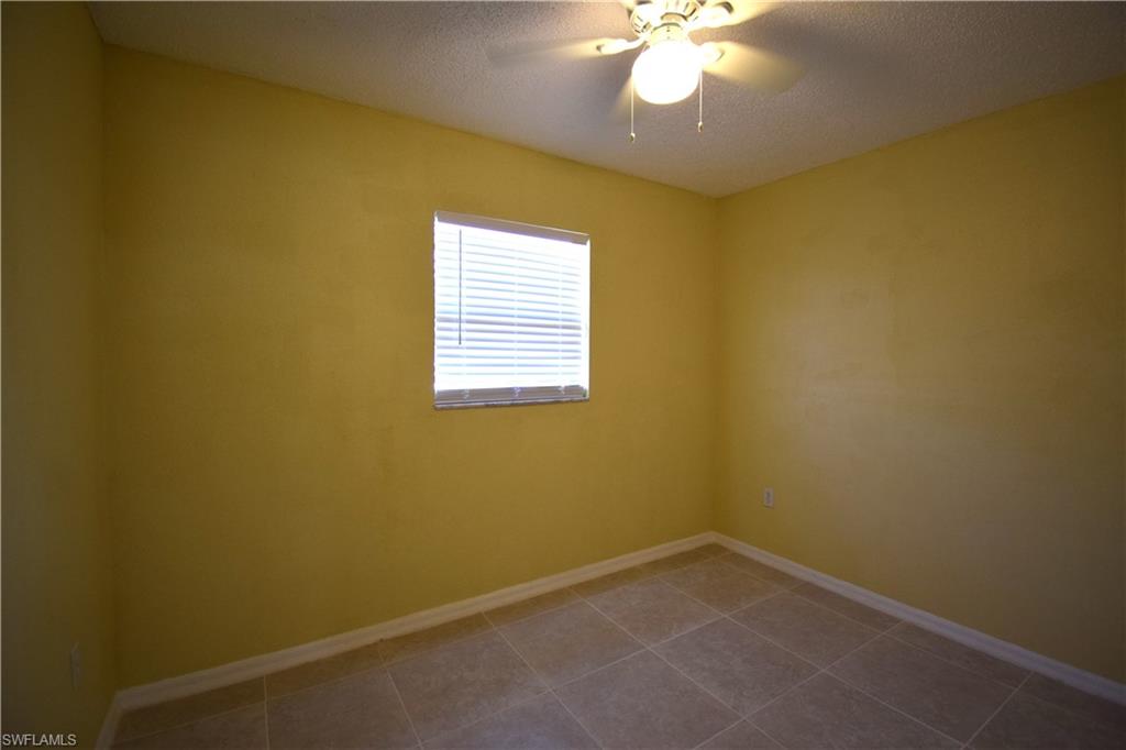 Room with tiled flooring, a single window with blinds, and a ceiling fan with integrated lighting