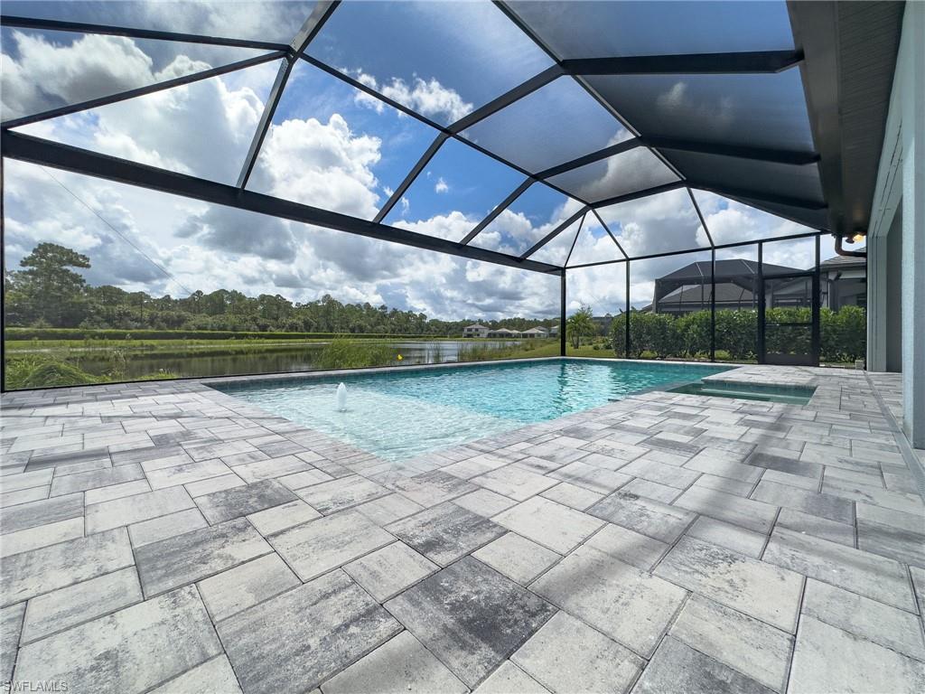 Screened outdoor living area featuring a rectangular pool with an integrated spa, a paver patio, and a water feature