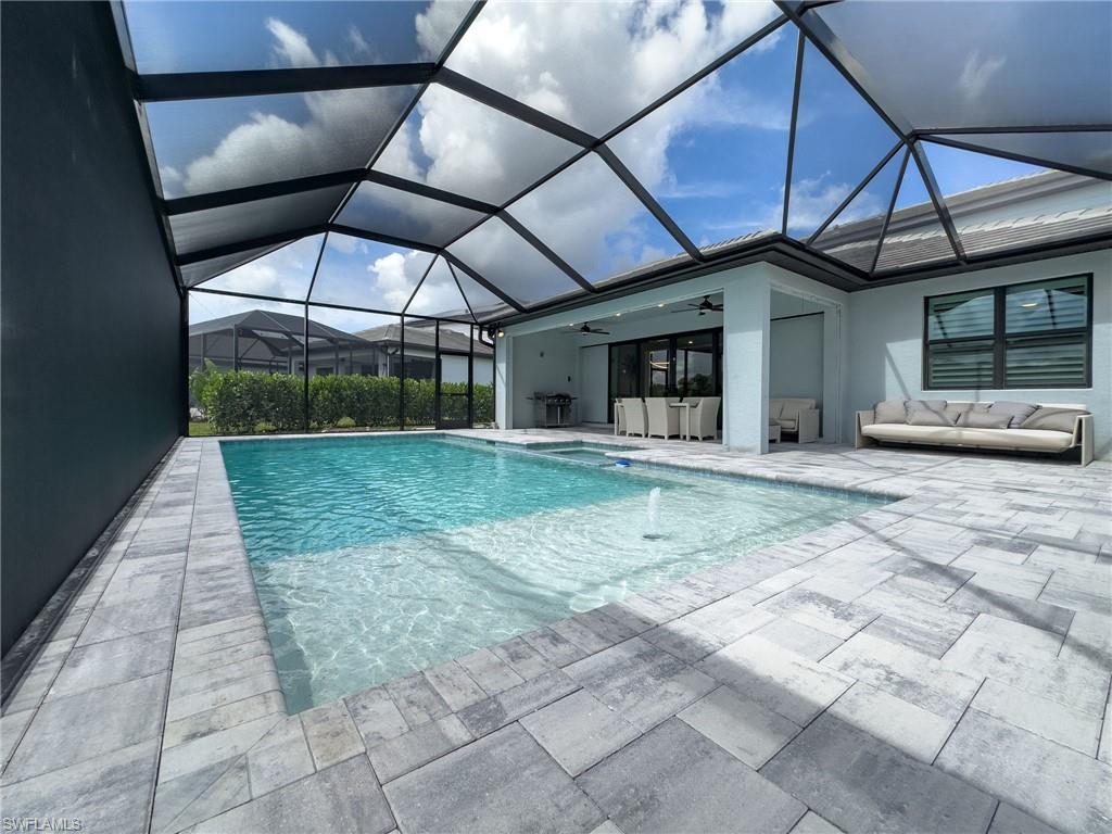 Screened pool enclosure with a rectangular swimming pool, integrated spa, and fountain feature