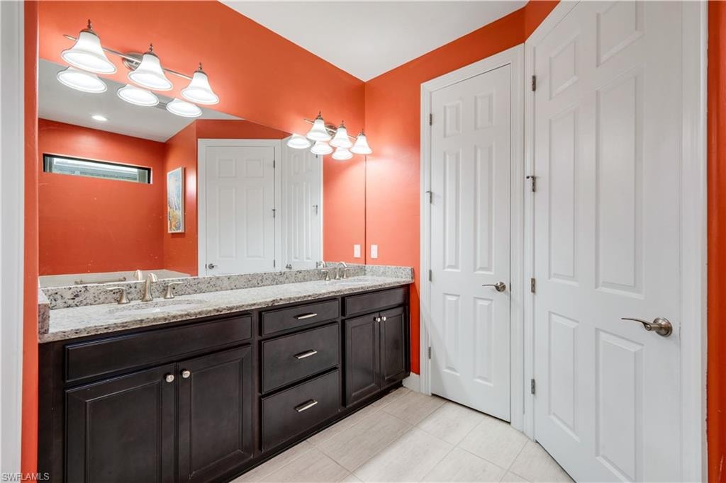 Dual vanity featuring dark wood cabinetry, granite countertops.