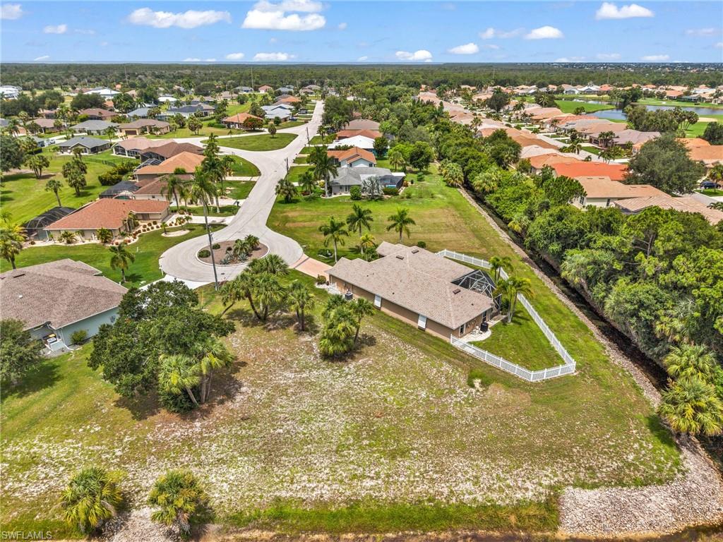 Spacious property featuring a single-story home with a screened lanai and pool, surrounded by mature palm trees