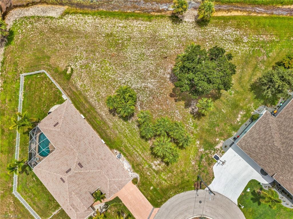 Expansive undeveloped parcel featuring mature trees, partial fencing, and a perimeter canal