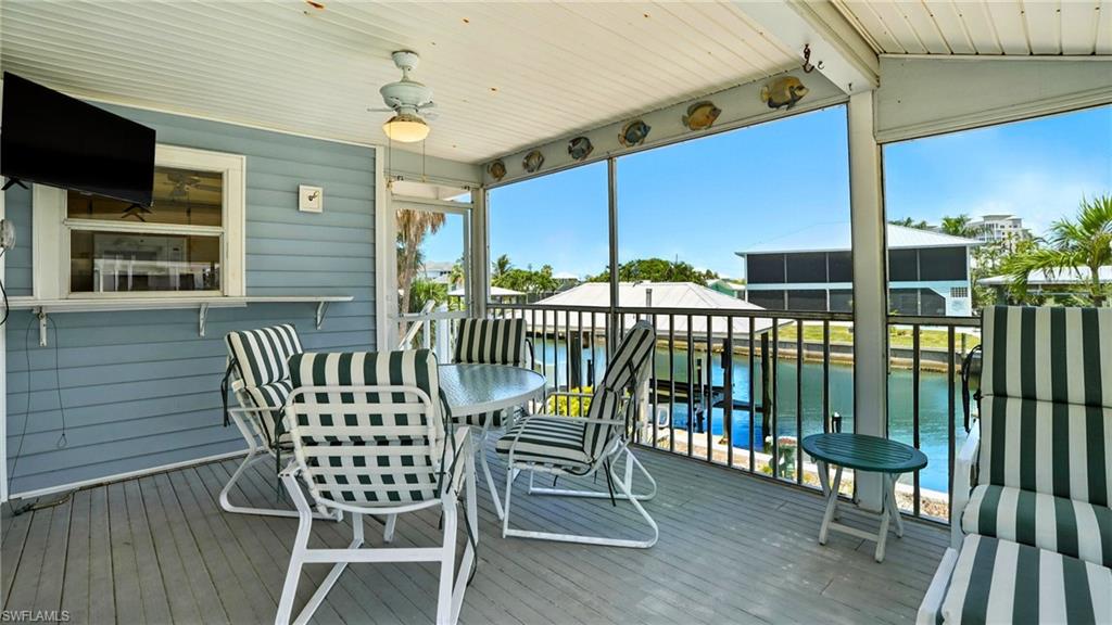 Sunroom / solarium with a water view, vaulted ceiling, and ceiling fan - Virtually Edited Image