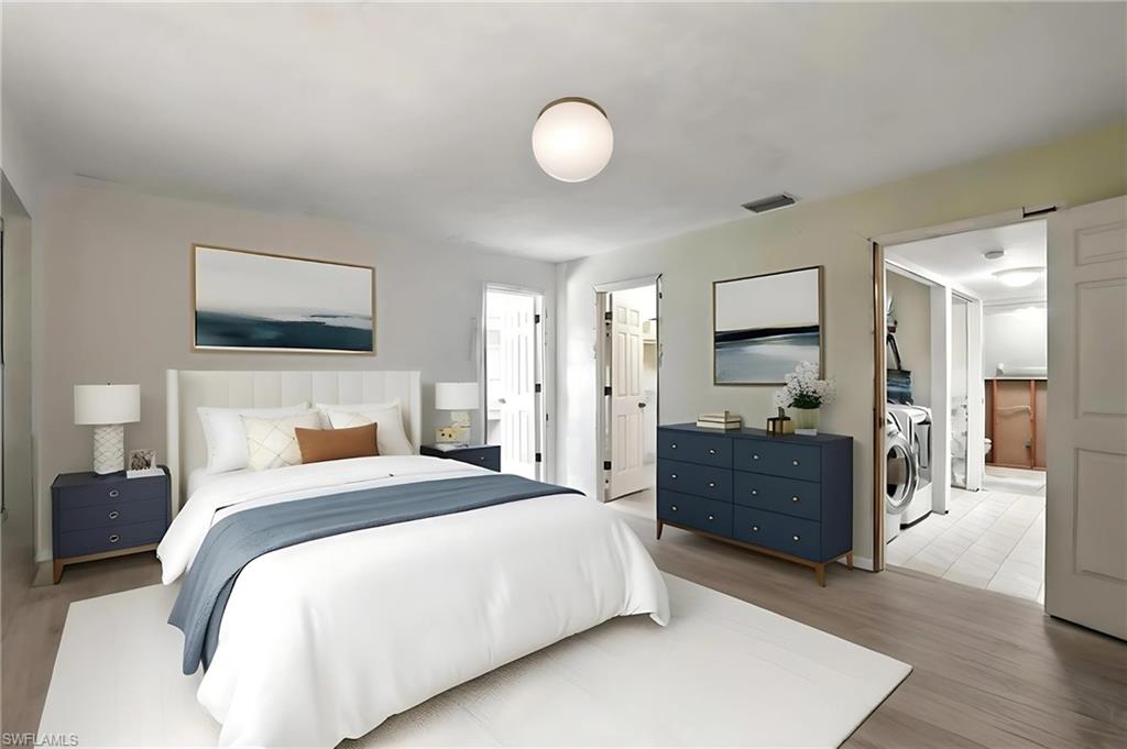 Bedroom 1 with separate washer and dryer, light wood-style floors, a walk in closet, and connected bathroom - Virtually Staged and Edited Image. first floor