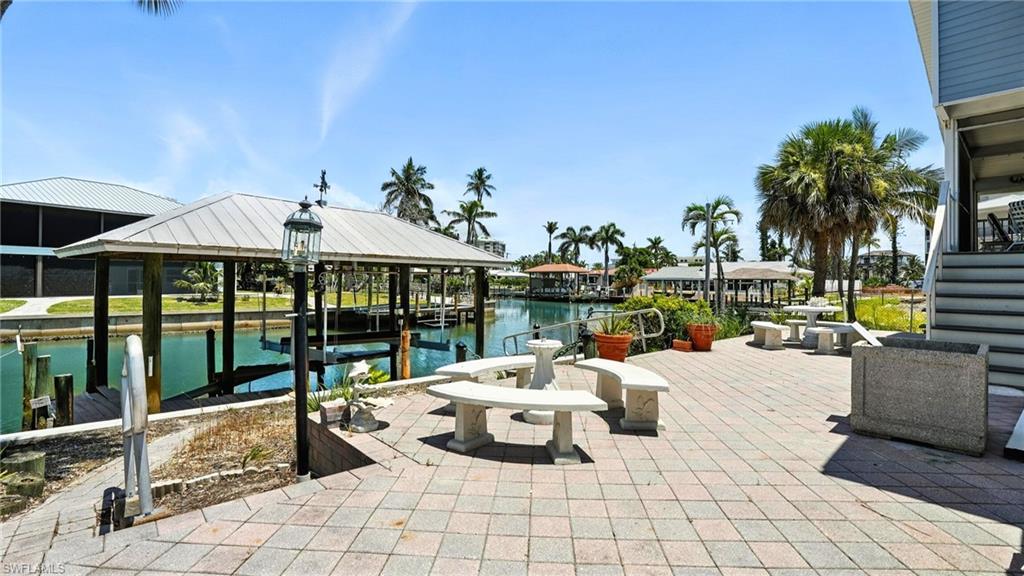 View of patio / terrace featuring boat lift, a boat dock, and a water view - Virtually Edited Image