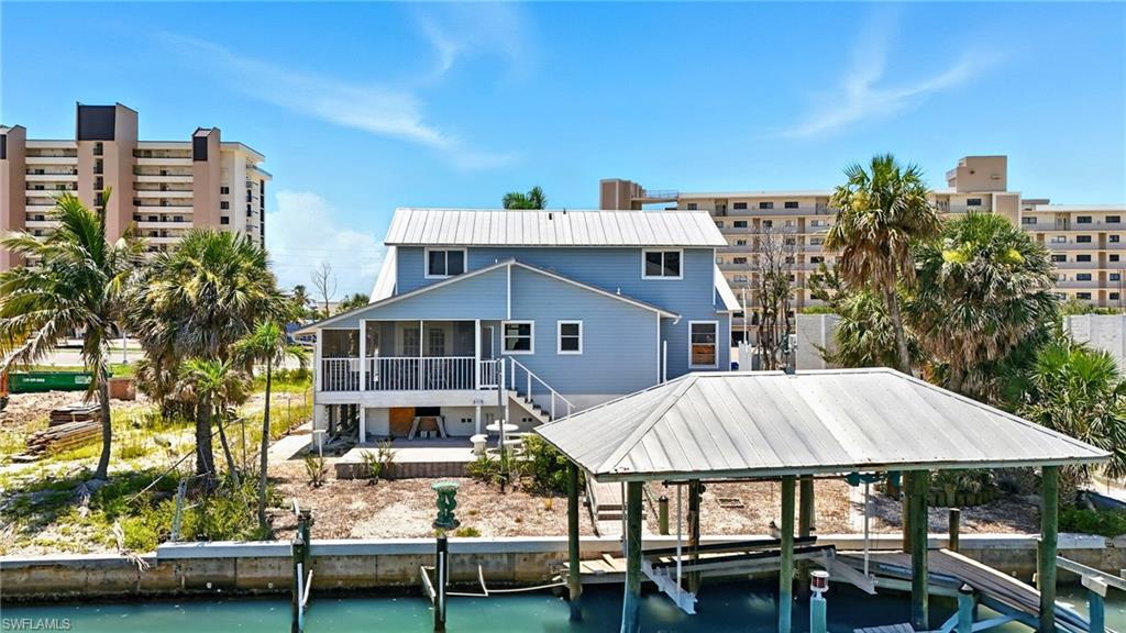 Back of property with a sunroom, a water view, stairway, and boat lift - Virtually Edited Image