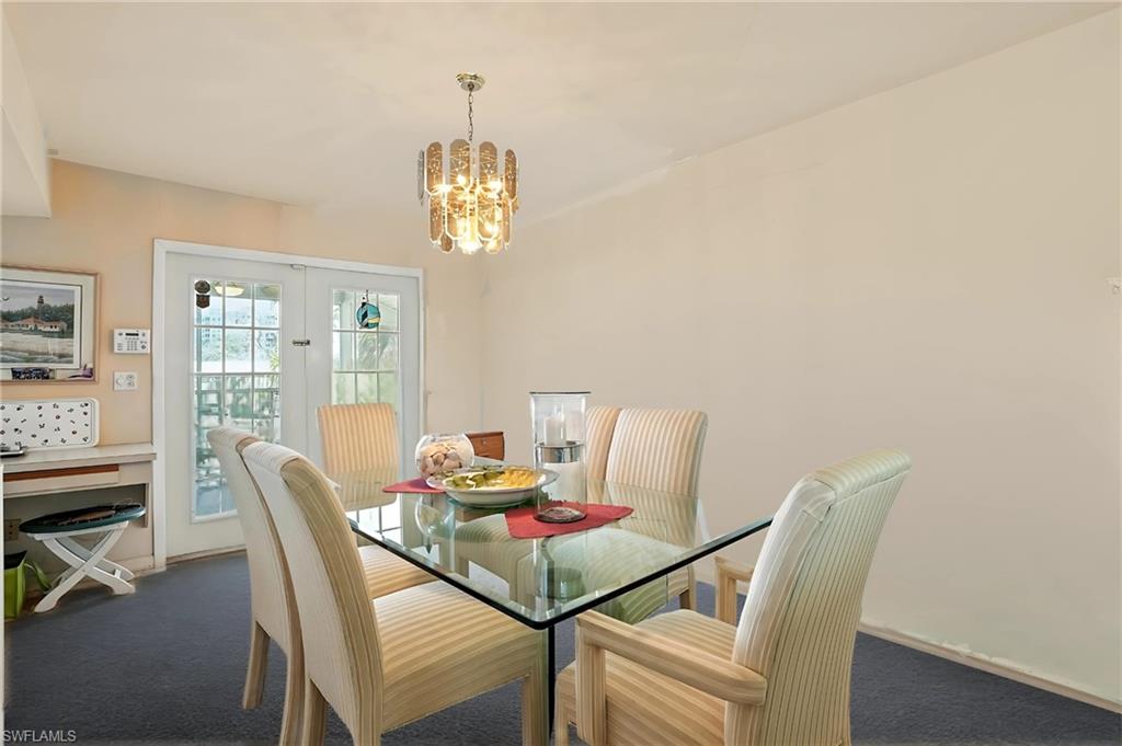 Carpeted dining room with a chandelier and french doors - Virtually Edited Image