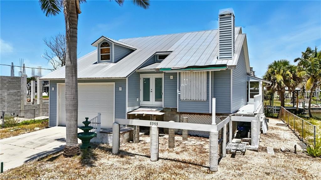 Back of property with french doors, driveway, a chimney, and a metal roof - Virtually Edited Image