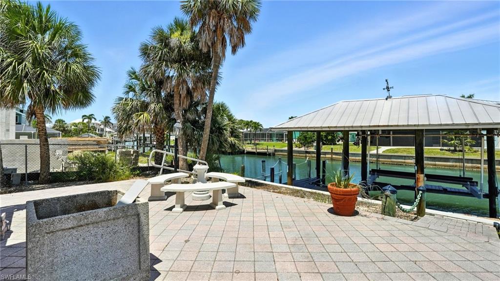 View of patio / terrace featuring a water view, a boat dock, and boat lift - Virtually Edited Image