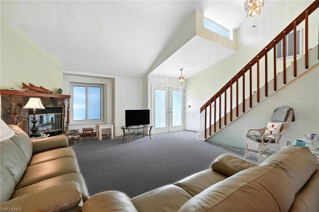 Carpeted living area with french doors, stairway, and a chandelier - Virtually Edited Image