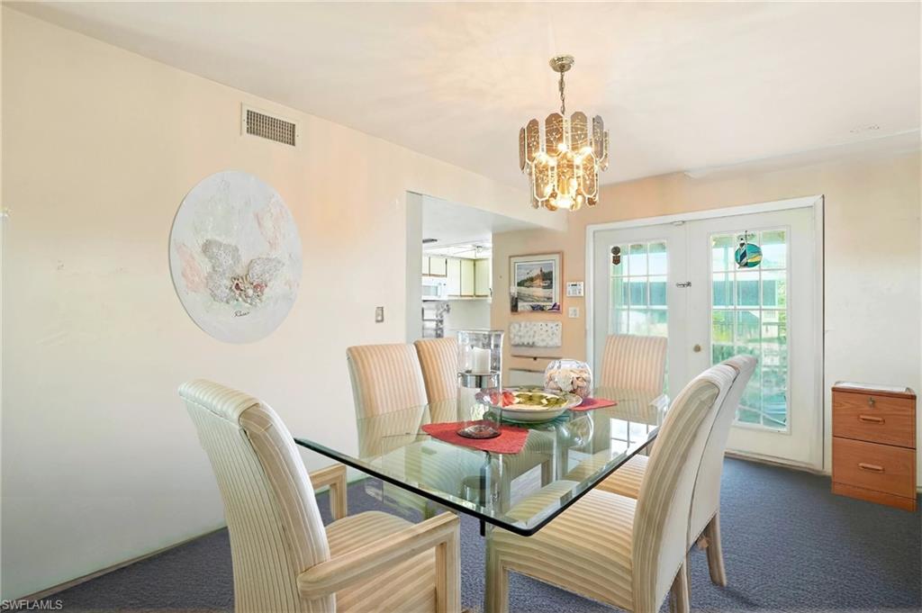 Carpeted dining area featuring french doors and a chandelier - Virtually Edited Image