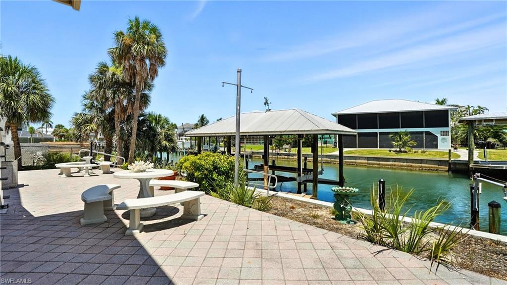 View of patio with a water view and boat lift - Virtually Edited Image