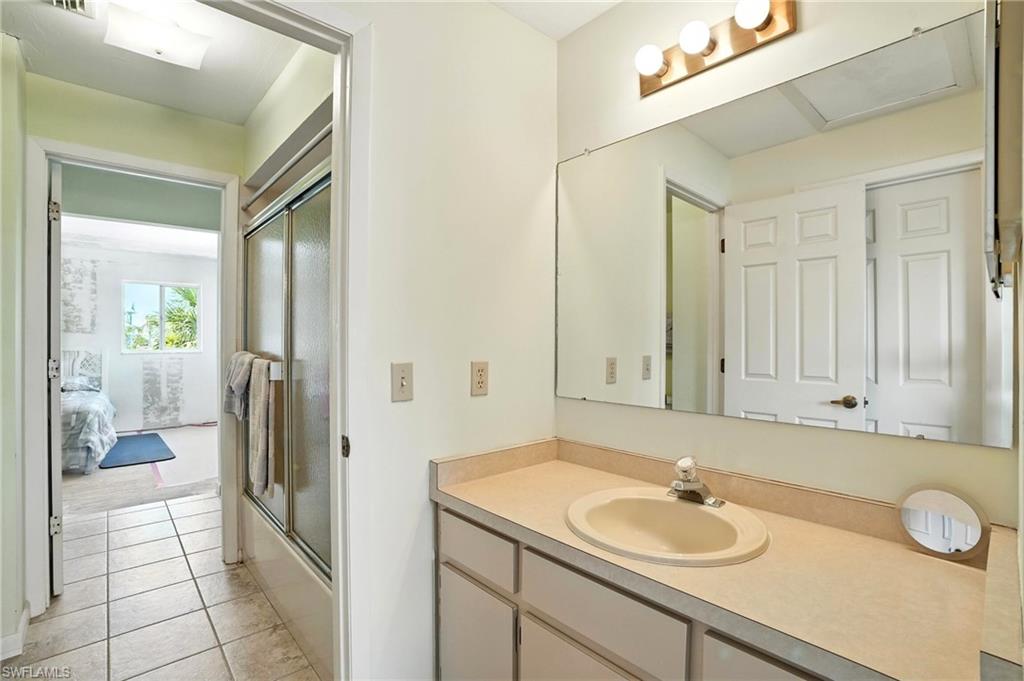 Full bath featuring vanity, tile patterned flooring, and combined bath / shower with glass door - Virtually Edited Image