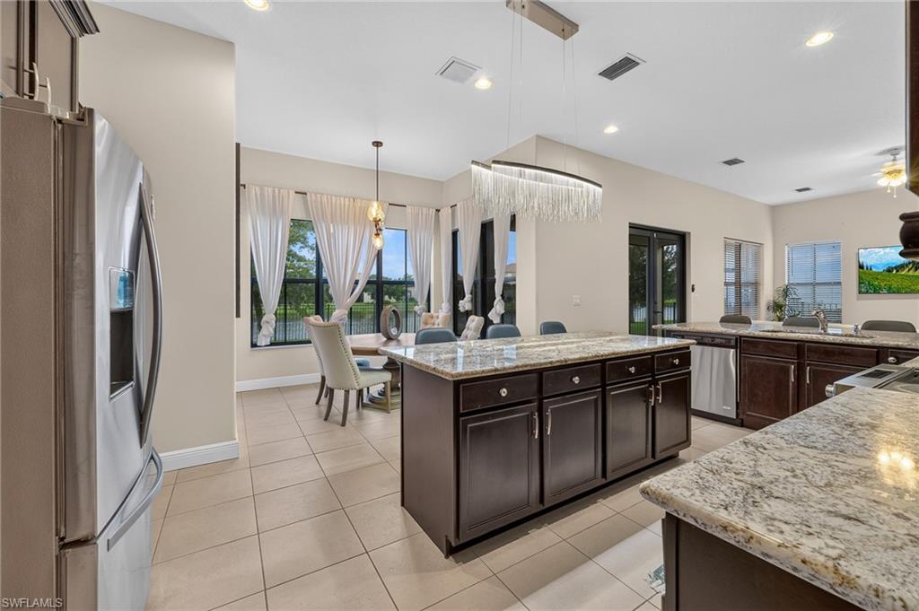 Kitchen featuring granite countertops, dark wood cabinetry, stainless steel appliances, and tile flooring