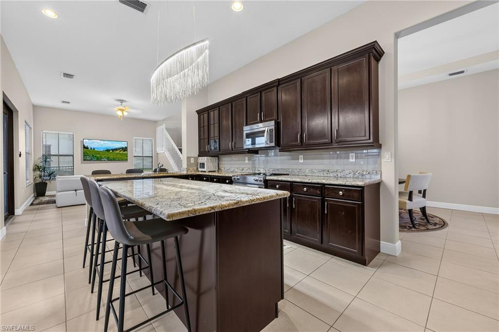 Kitchen featuring granite countertops, dark wood cabinetry, stainless steel appliances, and tile flooring