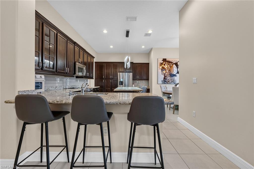 Kitchen featuring granite countertops, dark wood cabinetry, stainless steel appliances, and tile flooring